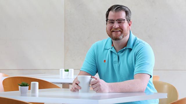 Todd Sitcler sits at table in Cafe Tempo with cup of coffee.