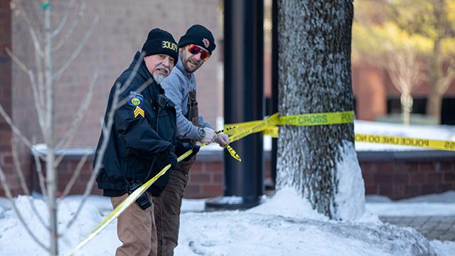 Two 赌钱app可以微信提现 police officers putting up crime scene tape